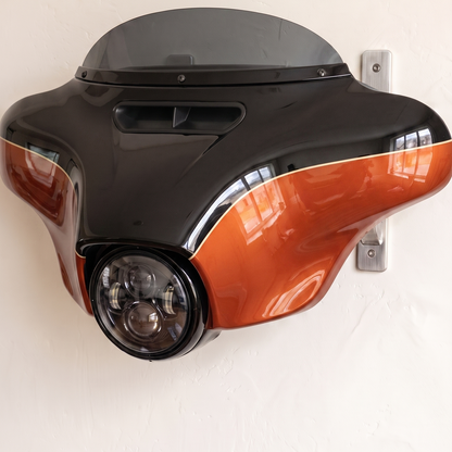 HarleyHood batwing fairing in orange and black two-tone on the wall bracket